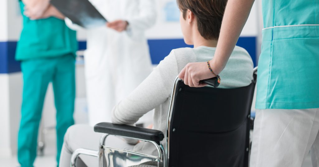 woman being pushed in a wheelchair by an attendant care worker
